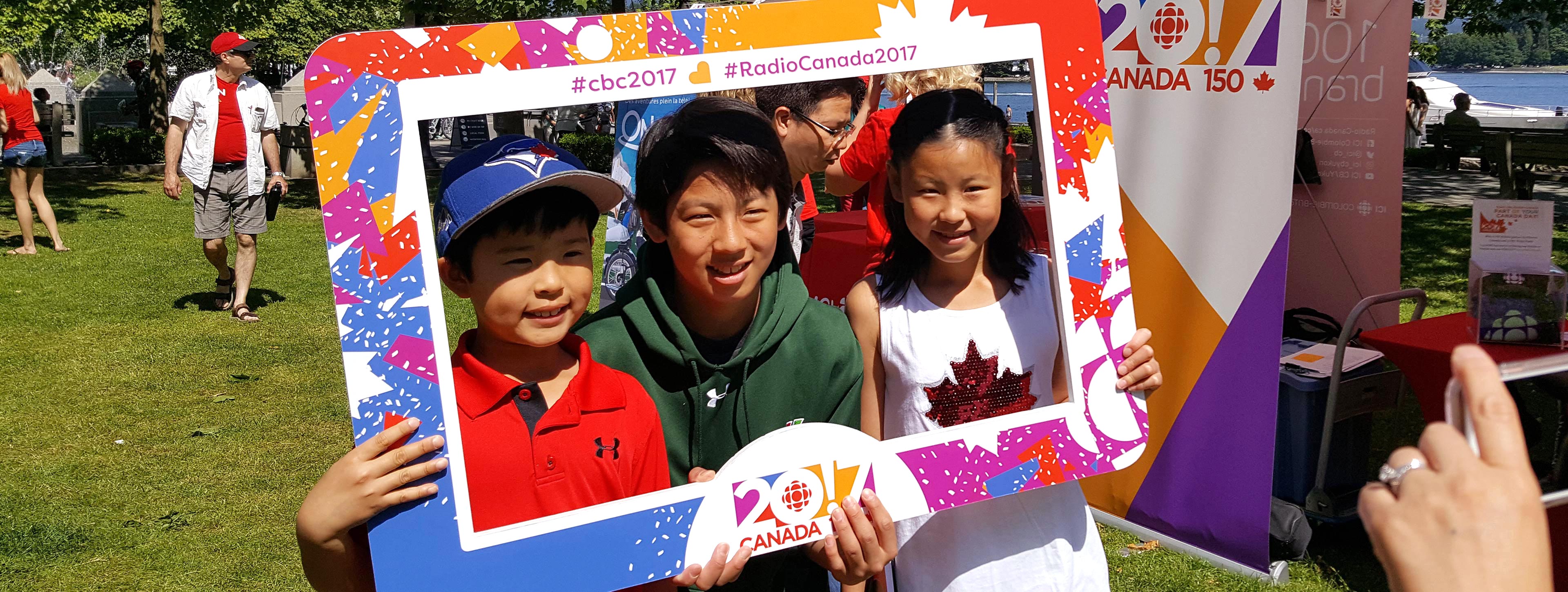 Des enfants photographiés derrière un cadre Canada 150.